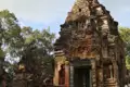 Kambodscha Radreise. Verwitterte Steinruine eines antiken Tempels mit detaillierten Schnitzereien am Eingang.