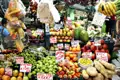 Marktstand mit tropischen Früchten und Gemüse wie Mangos, Bananen, Äpfeln, Birnen, Kiwis, Mandarinen, Guaven und Kartoffeln. Die Preise sind in Pesos angegeben.