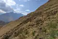 Wanderer auf einem grasbewachsenen Berghang mit Blick auf die Berge.