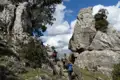 Wanderer auf einem Bergpfad mit Felsformationen und Geländer.