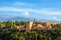 Auf unserer Reise bekommen wir einenPanoramablick auf die Alhambra mit ihren Türmen, Mauern und Gebäuden, eingebettet in die Landschaft der Sierra Nevada.