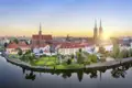 Die Dominsel in Breslau bei Sonnenaufgang, die Sie auf unserer Top-Preis-Reise besichtigen. Man sieht den Dom und historische Gebäude, die sich in der Oder spiegeln.