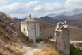 Historische Rundkirche und Burgruine inmitten einer bergigen Landschaft.