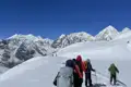 Wanderer mit Rucksäcken und Wanderstöcken in einer verschneiten Berglandschaft.