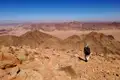 Ein Wanderer mit Rucksack wandert durch die felsige Wüstenlandschaft.