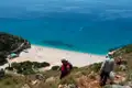 Wanderer auf einem Pfad mit Blick auf einen abgelegenen Strand.