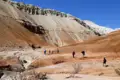 Wanderer auf einer Reise durchqueren eine rote Felslandschaft, die durch Erosion geformt wurde.
