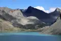 Türkisfarbener Bergsee umgeben von schroffen Gipfeln.