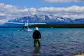 Wasserflugzeug landet auf einem See mit Bergen im Hintergrund.