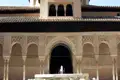 Maurische Architektur mit kunstvollen Bögen, Säulen und Ornamenten, zentriert um einen Brunnen.