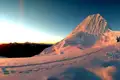 Schneebedeckter Berggipfel bei Sonnenaufgang mit Fußspuren im Vordergrund.