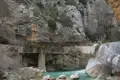 Wanderweg entlang einer Schlucht mit Wasserfall und türkisfarbenem Fluss.