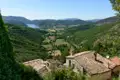 Panoramablick über ein Tal mit See und Häusern mit Ziegeldächern.