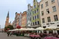 Blick entlang einer Straße mit bunten Häuserfassaden und Straßencafés in Richtung des Rathausturms.