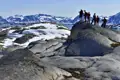 Farbenfrohe Häuser in einer Siedlung vor schneebedeckten Bergen.