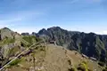 Gepflasterter Bergwanderweg mit Geländer und Blick auf die umliegende Berglandschaft.