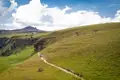 Wandergruppe auf einem Pfad in einer Hügellandschaft.