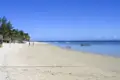 Weißer Sandstrand mit Palmen und Booten.