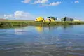 Campingplatz mit Zelten und Fahrzeug am Flussufer.