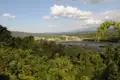 Ausblick auf einen Fluss, der sich durch den üppigen Regenwald schlängelt, umgeben von dichter Vegetation und Bergen im Hintergrund.