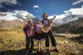 Einheimische Musiker in traditioneller Kleidung spielen vor der Kulisse der Anden.