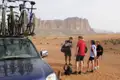 Radfahrergruppe pausiert in einer Wüstenlandschaft neben ihrem Begleitfahrzeug mit Fahrrädern auf dem Dachträger.