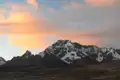 Schneebedeckte Gipfel einer Bergkette bei Sonnenuntergang.