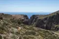 Eine Schlucht, die zum Meer führt, umgeben von niedriger Vegetation.