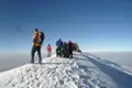 Wanderer erreichen den Gipfel eines schneebedeckten Berges.