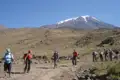 Wandergruppe auf einem Bergpfad in Richtung eines schneebedeckten Berggipfels.