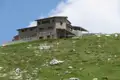 Steinhaus auf einem bewachsenen Hügel, möglicherweise Teil der Reiseunterkunft oder eine Station entlang der Route.