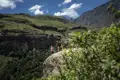 Wanderer auf einem Felsvorsprung mit Blick auf eine Berglandschaft.