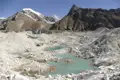 Türkisblaue Gletscherseen inmitten einer Hochgebirgslandschaft mit schneebedeckten Gipfeln im Hintergrund.