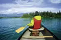 Kanufahrt auf einem See mit Bergen im Hintergrund.