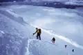 Bergsteiger beim Aufstieg eines verschneiten Berges, gesichert durch ein Seil.