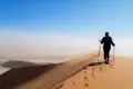 Wanderer mit Stöcken auf einer Düne.
