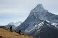 Wanderer auf einem Bergpfad, im Hintergrund ein schneebedeckter Berggipfel.