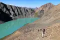 Wanderer auf einem Bergpfad in der Nähe eines türkisfarbenen Sees.