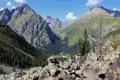 Wanderer auf einem Bergpfad mit Blick auf ein bewaldetes Tal und hohe Gipfel.