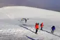 Wanderer mit Winterausrüstung besteigen einen verschneiten Berghang.