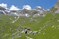 Wanderer auf einem Bergpfad mit schneebedeckten Gipfeln im Hintergrund.