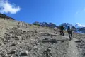 Wanderer auf einem steinigen Pfad in den Bergen. Schneebedeckte Gipfel im Hintergrund.