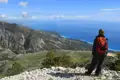 Wanderer auf einem Berggipfel mit Blick auf die Küste und das türkisblaue Meer.