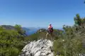 Wanderer auf einem felsigen Gipfel mit Blick auf die Küste.