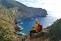 Wanderer pausiert auf einem Felsen und betrachtet die Küste.