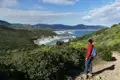 Wanderer auf einem Küstenpfad mit Blick auf das Meer und die Berge.