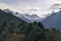 Schneebedeckte Gipfel und bewaldete Hänge.