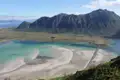 Panoramablick auf die Küstenregion mit türkisfarbenem Wasser, Sandbänken und Bergen im Hintergrund.