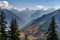 Herbstlandschaft in den Bergen mit bunten Bäumen und majestätischen Gipfeln.