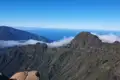 Blick über die Berglandschaft mit Wolkenformationen und Meer.
